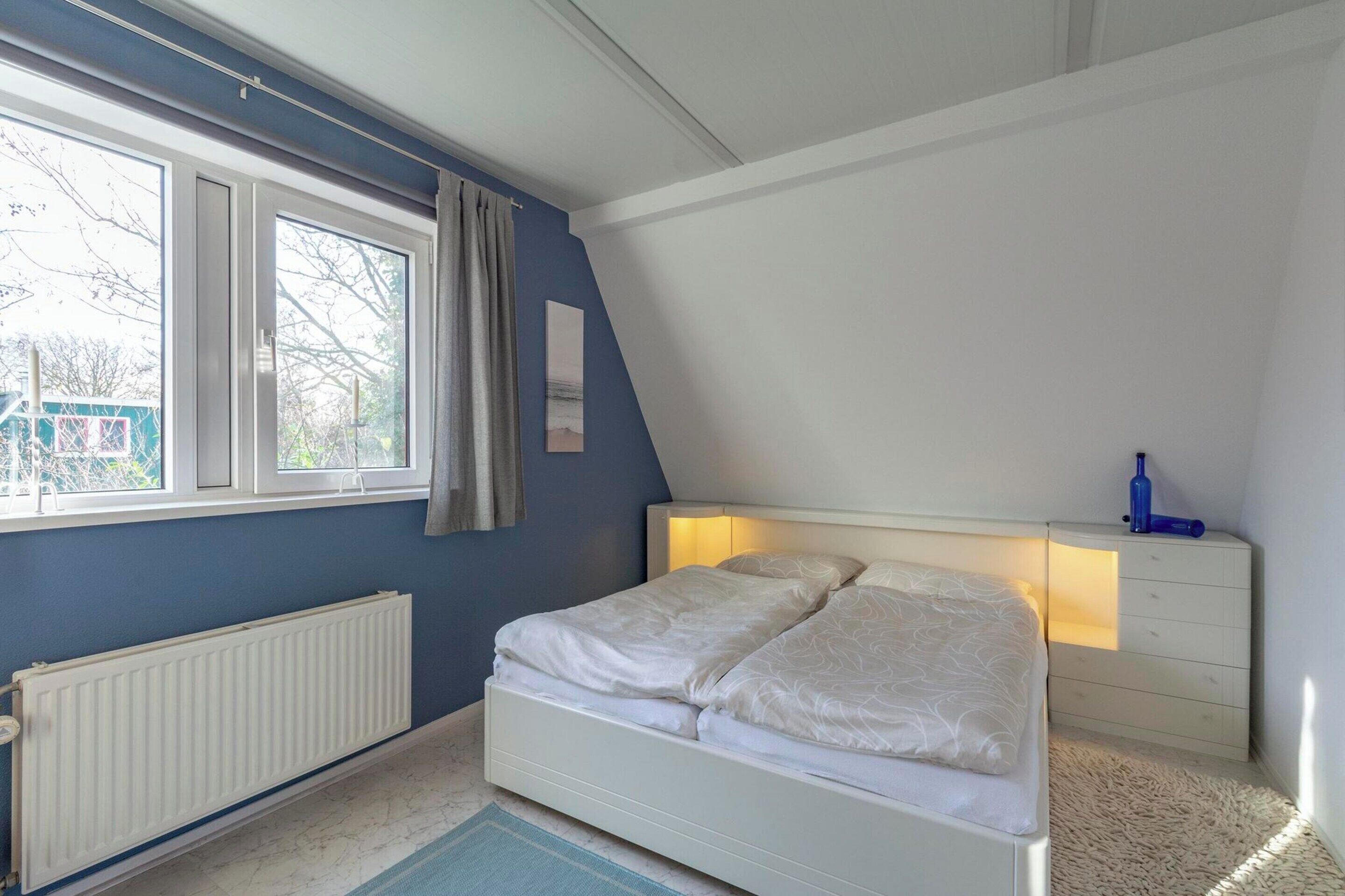 Un dormitorio con cama, ventana, radiador y cómoda.