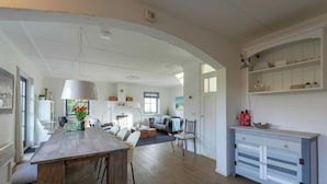 Amplia sala de estar con una mesa de comedor de madera, un sofá y un gabinete blanco empotrado con estantes.