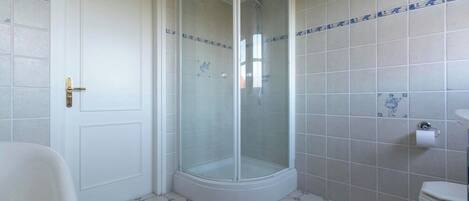 A bathroom with a glass-enclosed shower, a toilet, and a sink.