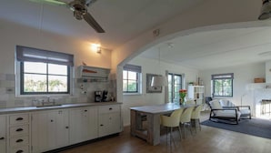 Una cocina moderna con armarios blancos, una mesa de comedor de madera y un ventilador de techo.