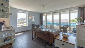 A modern kitchen with a dining area, large windows, and a view of the outside. - Callantsduyne 21 With Groote Keeten Dune View (Callantsoog)