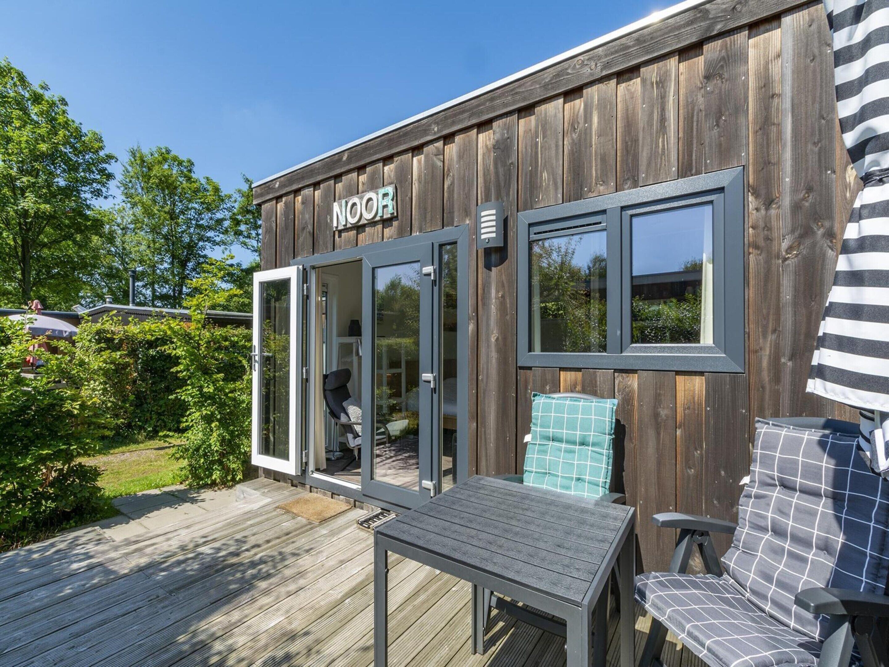 A wooden building with a sign reading 'NOOR' and a sliding glass door entrance.