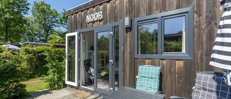 A wooden building with a sign reading 'NOOR' and a sliding glass door entrance.