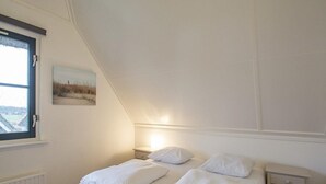 A bedroom with two beds, a nightstand, a window, and a painting on the wall. - Villa With View Over the Park De Buitenplaats (Callantsoog)