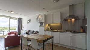 A modern kitchen with a dining area, large windows, and a view of the outdoors. - Apartment Near Groote Keeten Beach (Callantsoog)