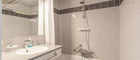 A bathroom with a sink, mirror, shower, and bathtub.
