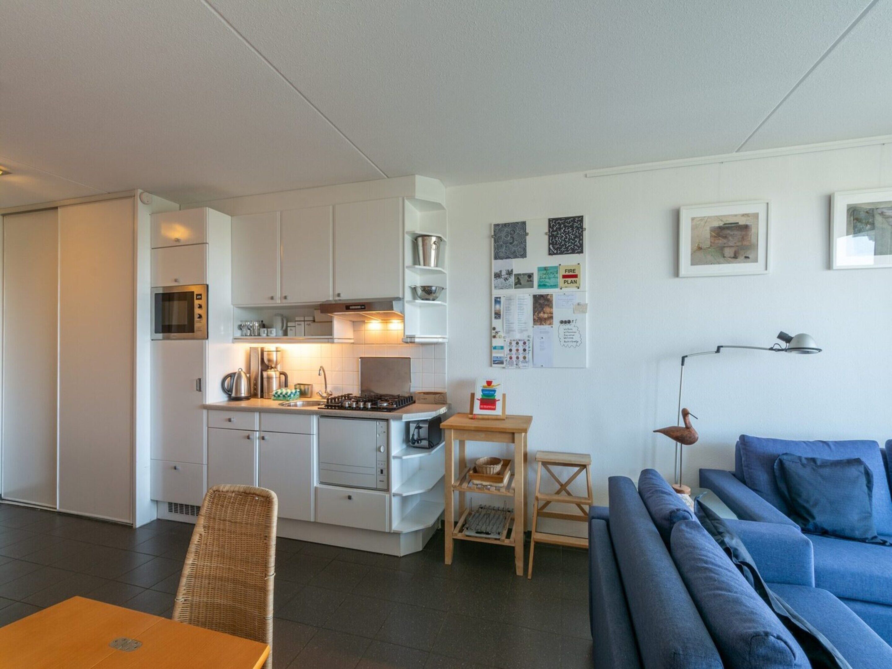 A compact living space with a kitchenette, a dining area, and a seating area with a blue sofa.