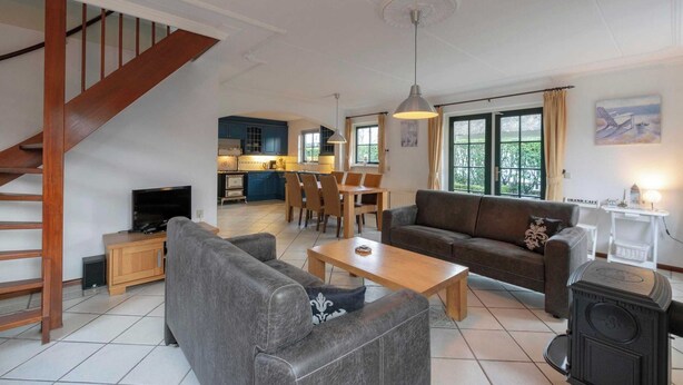 A spacious living area with a sofa, coffee table, and a fireplace. A staircase leads to an upper level.