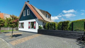 A two-story house with a steep roof, a small front porch, and a paved driveway.