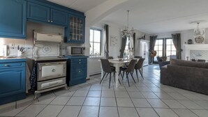 A kitchen with blue cabinets, a white stove, and a dining table with chairs. - Villa in Callantsoog Near Beach & Sea (Callantsoog)
