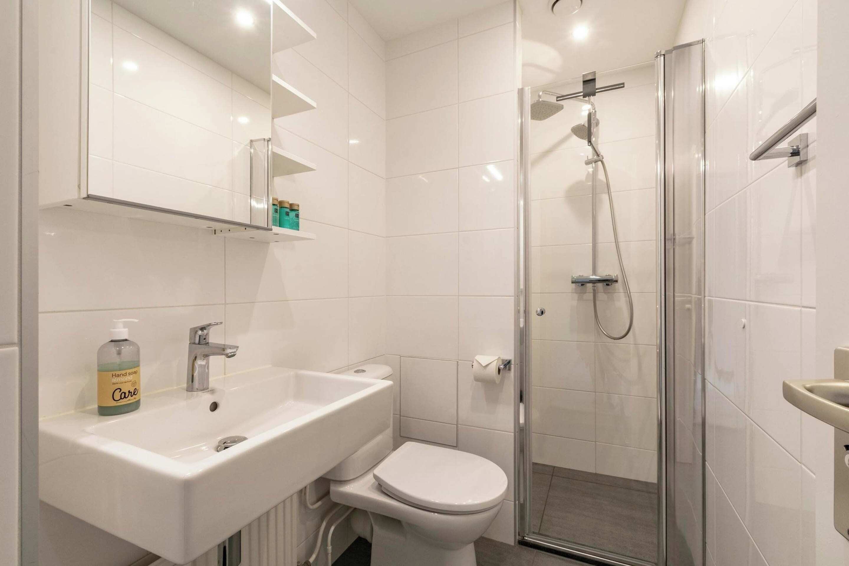 Ein modernes Badezimmer mit weißem Waschbecken, WC und einer Duschkabine.