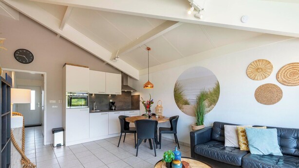 A modern living room with a sofa, coffee table, and dining area. - Apartment in Callantsoog by the Beach (Callantsoog)