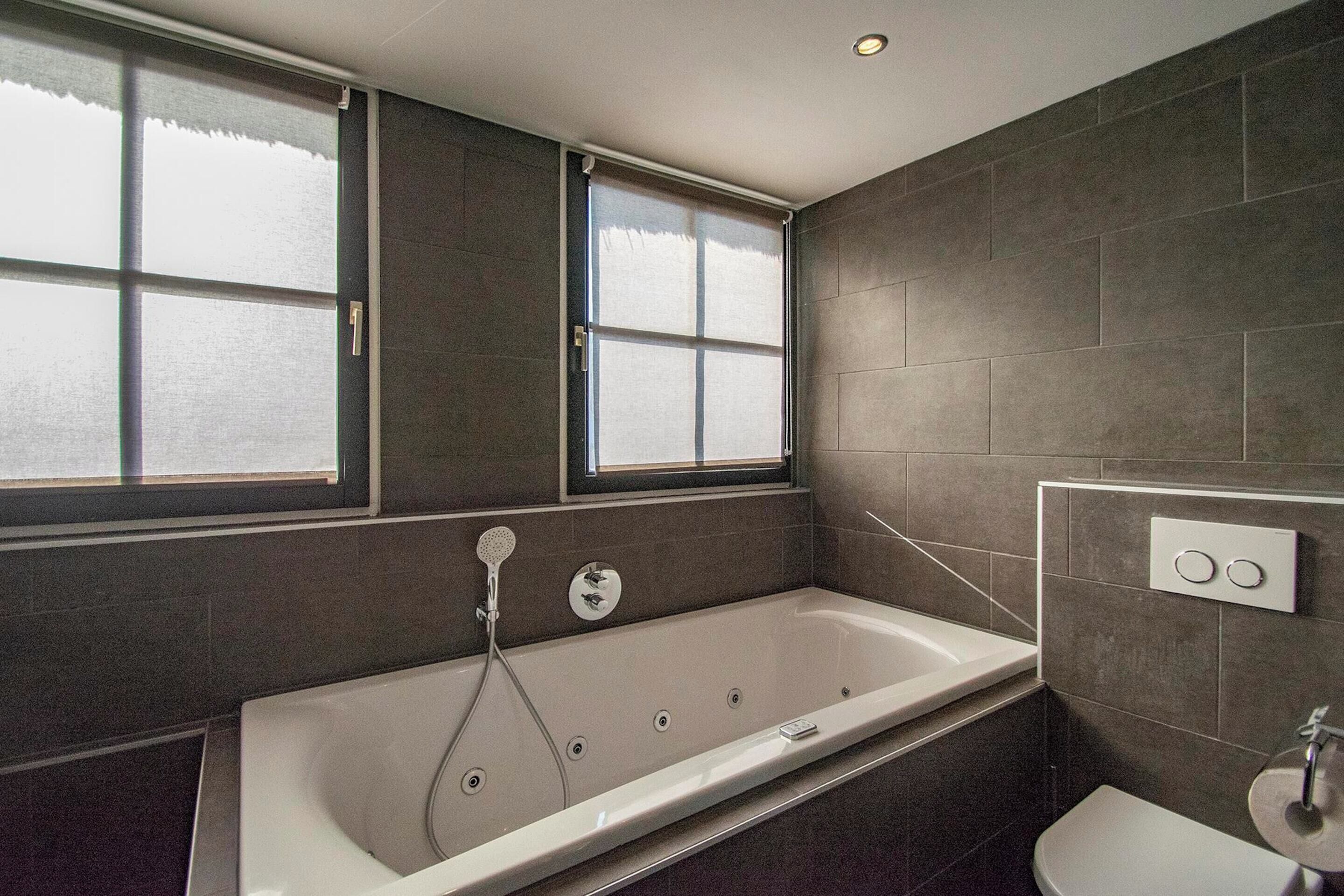 Un bagno moderno con una grande vasca, una finestra e il water.