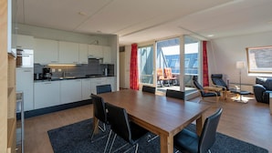Une cuisine moderne avec des meubles blancs et un coin repas comprenant une table en bois et des chaises noires.
