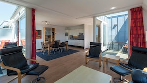Un salon moderne avec un coin repas, de grandes fenêtres et un balcon.