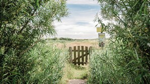 A wooden gate leading into a field with tall grass and trees. - Beach Lodge Callantsoog Near the Sea (Callantsoog)