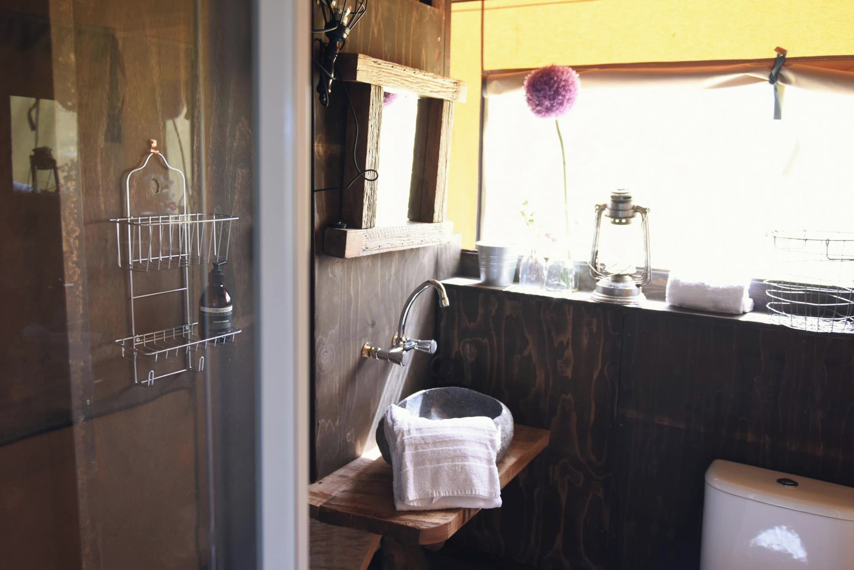 A bathroom with a wooden vanity, a sink, a mirror, and a window with a view of the outside.