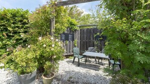 Une terrasse de jardin agrémentée d’une pergola en bois, d’une table et de chaises.