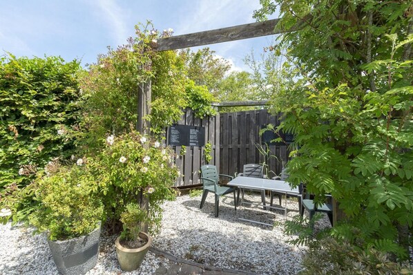 A garden patio with a wooden pergola, a table, and chairs. - Holiday Villa at Park De Buitenplaats (Callantsoog)
