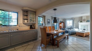 A spacious kitchen with a dining area, large windows, and a fireplace. - Dutch Beach Hideaway w/ Parking (Callantsoog)