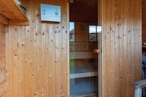 L’intérieur d’une cabane en bois, avec un thermostat visible, une fenêtre et une porte.