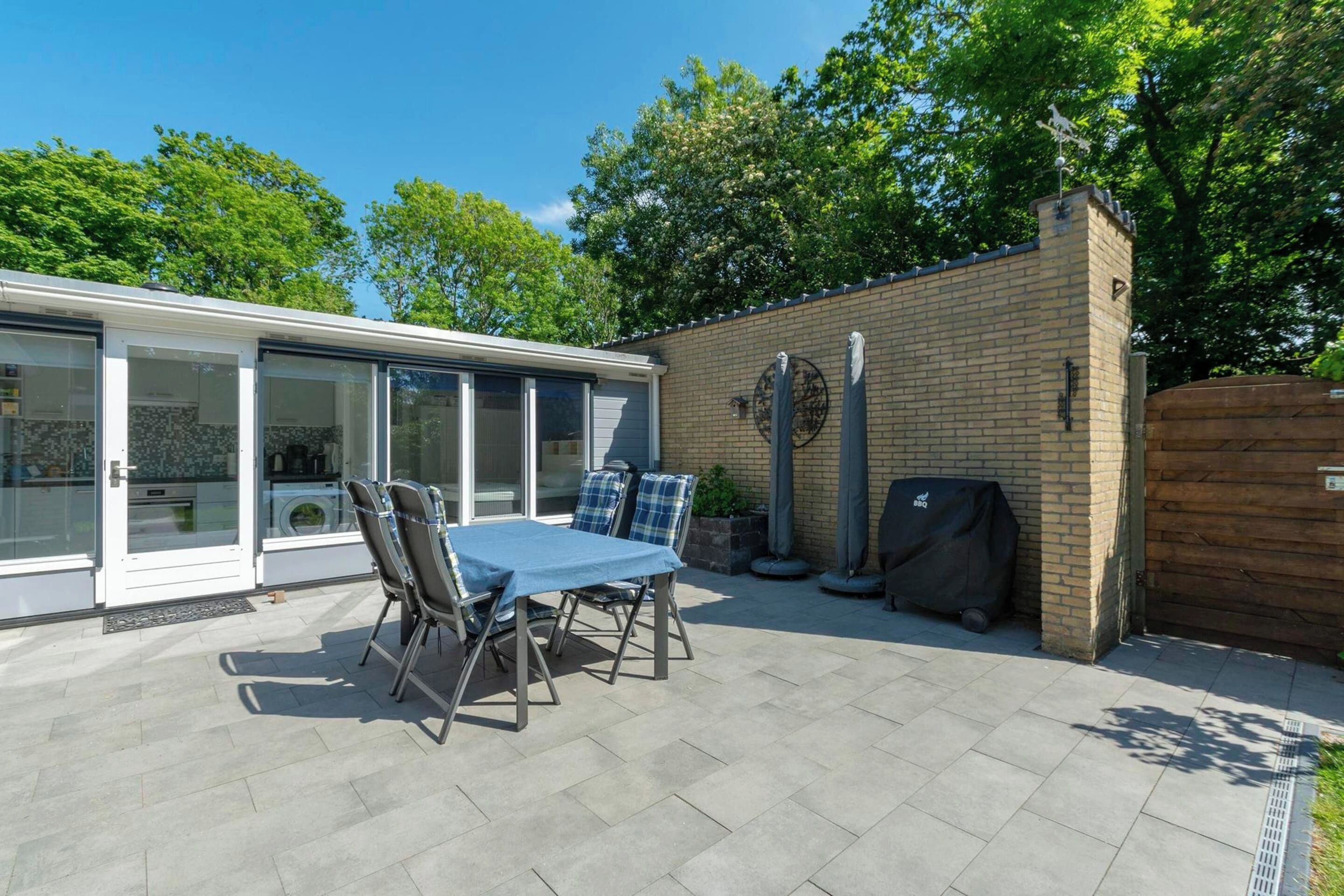 A patio with a table and chairs, a brick wall, and a covered grill area.