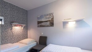 A room with two beds, a wall-mounted shelf with a lamp, and a framed picture on the wall. - Bungalow in Sint Maartenszee Near Beach (Sint Maartensvlotbrug)