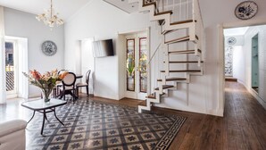 A spacious living room with a patterned rug, a staircase, and a dining area with chairs and a table. - La Perla del Duomo With Terrace by Wonderful Italy (Catania)