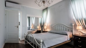 A bedroom with a bed, bedside tables, a mirror, and a chandelier. - La Perla del Duomo With Terrace by Wonderful Italy (Catania)