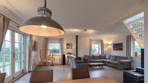 A spacious living area with a large dining table, sofas, and a staircase. - Villa in Callantsoog Near Beach and Dunes (Callantsoog)