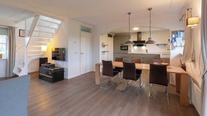 A modern apartment with a dining area, kitchen, and a staircase leading to an upper floor. - Villa in Callantsoog Near Beach and Dunes (Callantsoog)