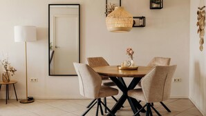 A dining area with a round table, four chairs, a hanging light fixture, and a framed picture on the wall. - Comfortable 2-guest De Vlijt First Class Suite (De Cocksdorp)