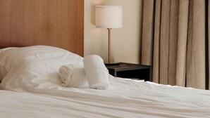 A neatly made bed with white linens, a wooden headboard, a bedside table with a lamp, and a window with curtains. - Comfortable 2-guest De Vlijt First Class Suite (De Cocksdorp)