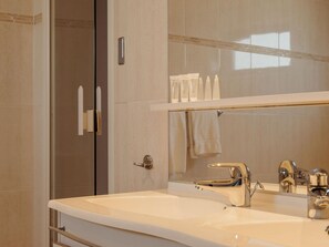 A bathroom with a large mirror, a sink, and a shower area.