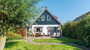 A house with a dark roof, white walls, and red and white window frames. There is a lawn with a pathway leading to the house, and a tree to the left. - De Buitenplaats 7 Villa With Dune Views (Callantsoog)