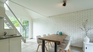 Une cuisine moderne avec un îlot central en bois, des murs en briques blanches et un coin repas comprenant une table et des chaises en bois.