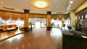 A hotel lobby with a reception desk, seating area, and large windows. - Chunjiang Hotel (Dangyang)