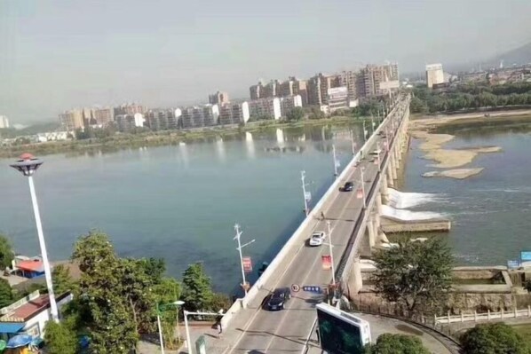 A bridge with a river on one side and buildings in the distance. - Chunjiang Hotel (Dangyang)