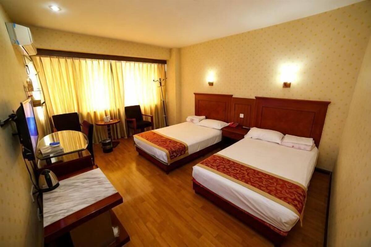 Habitación de hotel con dos camas, un escritorio, una silla, un televisor y una ventana con cortinas.