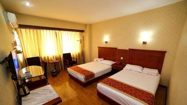A hotel room with two beds, a desk, a chair, a TV, and a window with curtains. - Chunjiang Hotel (Dangyang)