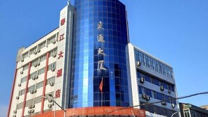 Ein mehrstöckiges Gebäude mit einer auffälligen blauen Glasfassade und Hinweisschildern, die es als Hotel kennzeichnen.