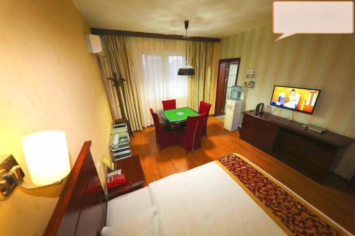 Habitación de hotel con una cama, un escritorio con computadora, un televisor y una mesa de comedor.