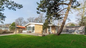 A modern house with a patio, a barbecue area, and a well-maintained lawn.