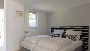 Une chambre à coucher avec un lit, une fenêtre avec des rideaux, un radiateur et un tableau accroché au mur.