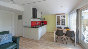 Un espace de vie compact comprenant un coin cuisine, un espace repas et une grande fenêtre offrant une vue dégagée.