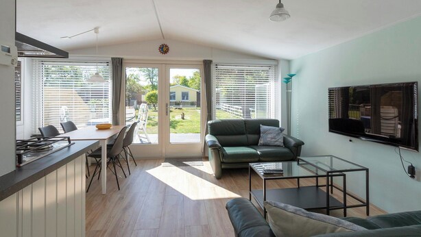 Un salon moderne avec un canapé, une table basse en verre et un téléviseur fixé au mur.