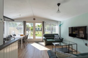 Una sala de estar moderna con un sofá, una mesa de centro de vidrio y un televisor en la pared.