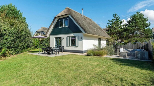 A house with a thatched roof, a number 16, and a patio with outdoor furniture. - Duynopgangh 16 Villa for 8-guests Behind Dunes (Julianadorp)