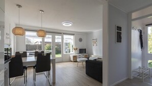 A modern kitchen with a dining area, a sofa, and a TV. - Modern Holiday Home With Large Garden (Sint Maartensvlotbrug)
