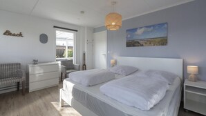 A bedroom with two beds, a dresser, a chair, a lamp, and a painting on the wall. - Modern Holiday Home With Large Garden (Sint Maartensvlotbrug)